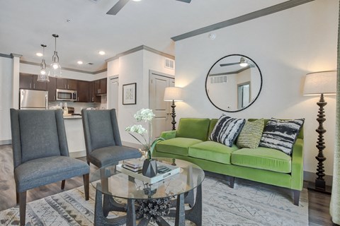 a living room with a green couch and a glass coffee table